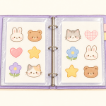 Open lavender binder holding kawaii sticker sheets on their backing paper inside clear protective sleeves.