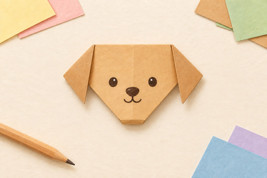 Illustration of a tan origami dog face with floppy ears, round eyes, and a small smile, surrounded by pastel paper.