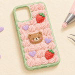 Drawing of a mint phone case decorated with pink cream piping, a bear charm, two strawberries, and lavender hearts.