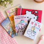 Collection of Chiikawa, Hello Kitty, Pusheen and Sumikko Gurashi books arranged on a pastel desk