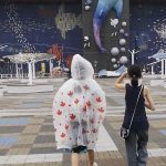 Two teenagers seen from behind walking toward Osaka Aquarium Kaiyukan in Japan