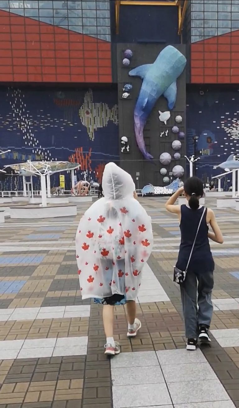 Two teenagers seen from behind walking toward Osaka Aquarium Kaiyukan in Japan