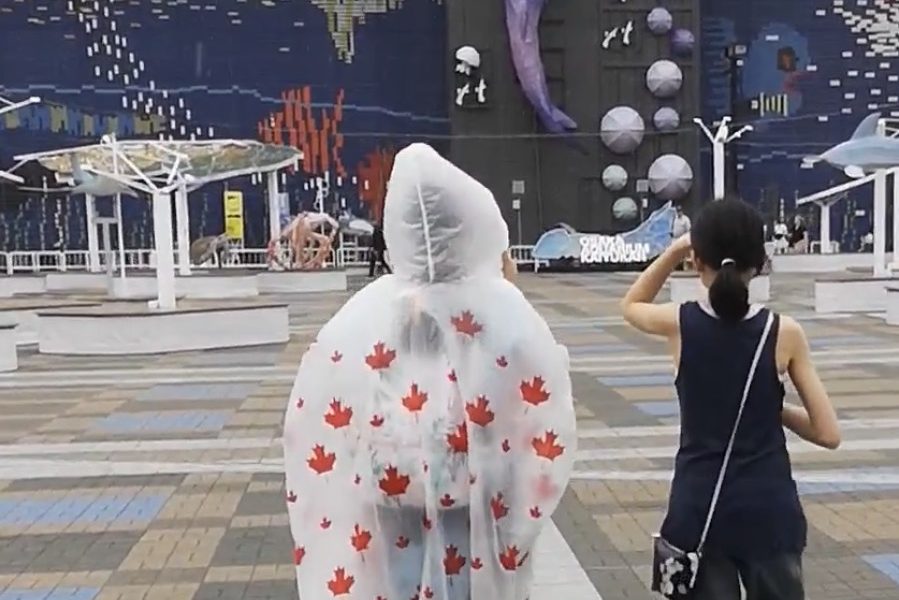 Two teenagers seen from behind walking toward Osaka Aquarium Kaiyukan in Japan